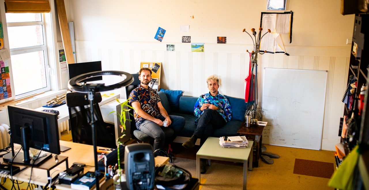 De broers van Duo Bottasso zitten op een bank in hun studio, omgeven door apparatuur