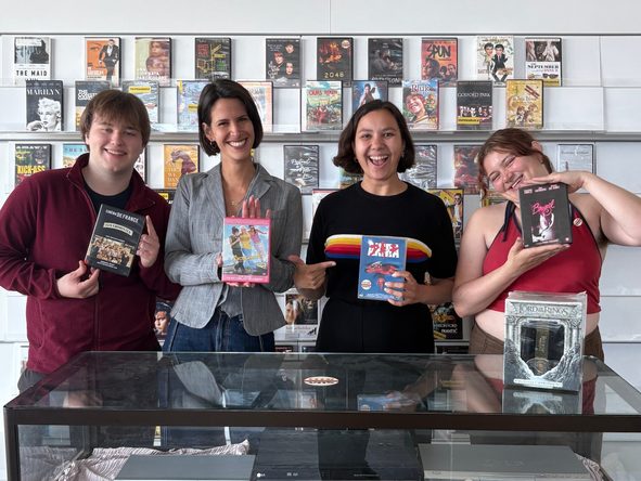 Vier medewerkers van Club VHS poseren met een dvd