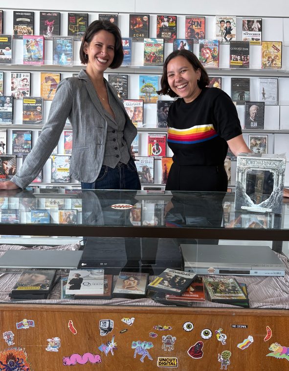 Eli en Ismay poseren met een vitrine en een muur vol dvd's