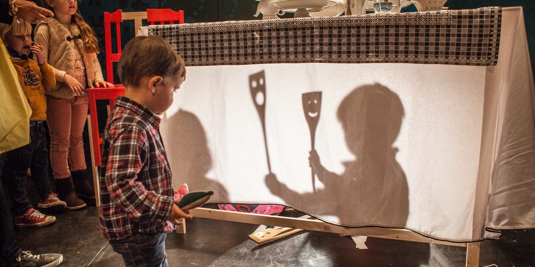 Een jongetje maakt figuren met zijn schaduw