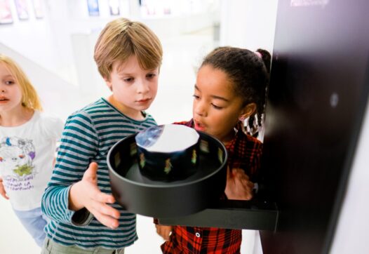 Drie kinderen bekijken een optische illusie die deel uitmaakt van de permanente tentoonstelling in Eye Filmmuseum