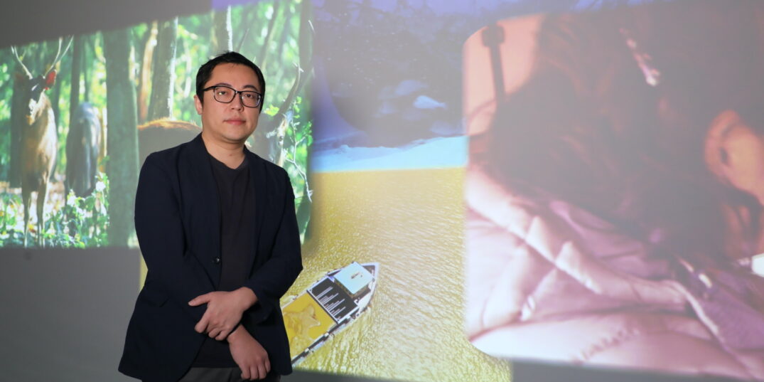Portretfoto van Chia-Wei Hsu, hij poseert voor een wand met projecties